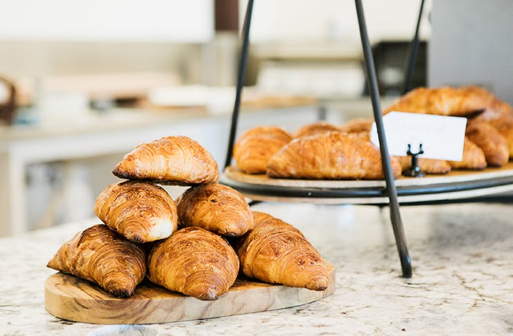A pile of croissants on a bench top.