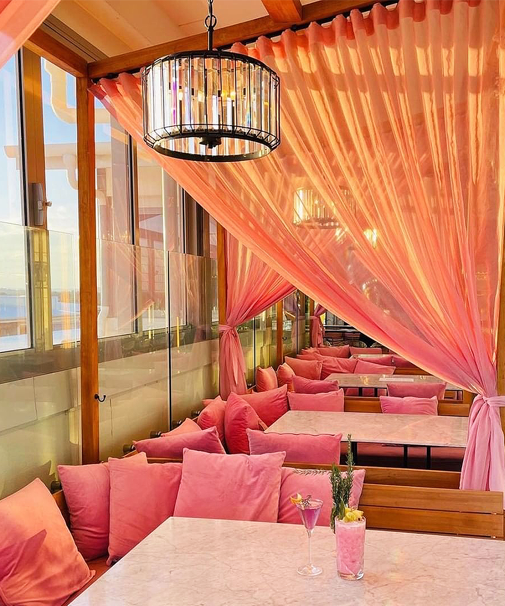 a rooftop bar with pink curtains