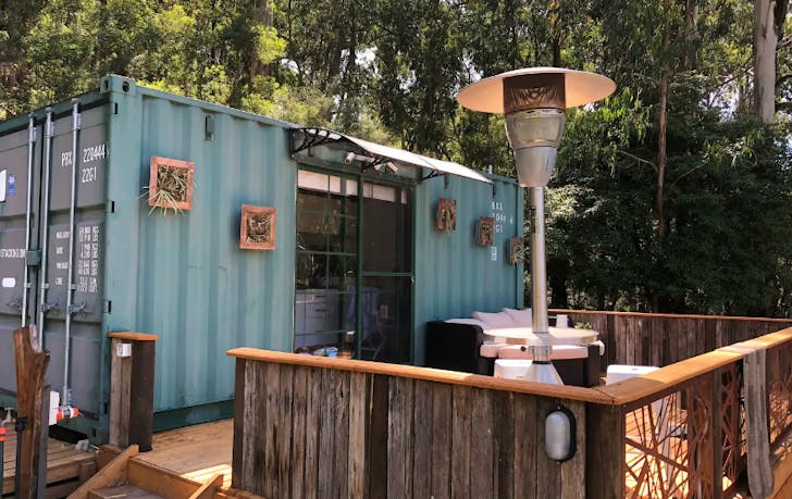 A converted shipping container with trees at one of the best farm stays Victoria has.