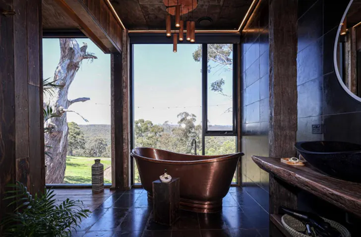 A bath sits in the centre of a romantic bathroom, looking out to mountain views.