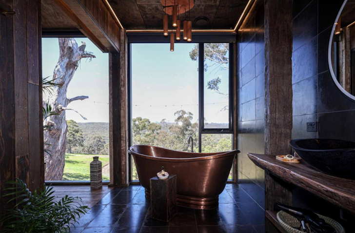 A bath sits in the centre of a romantic bathroom, looking out to mountain views.
