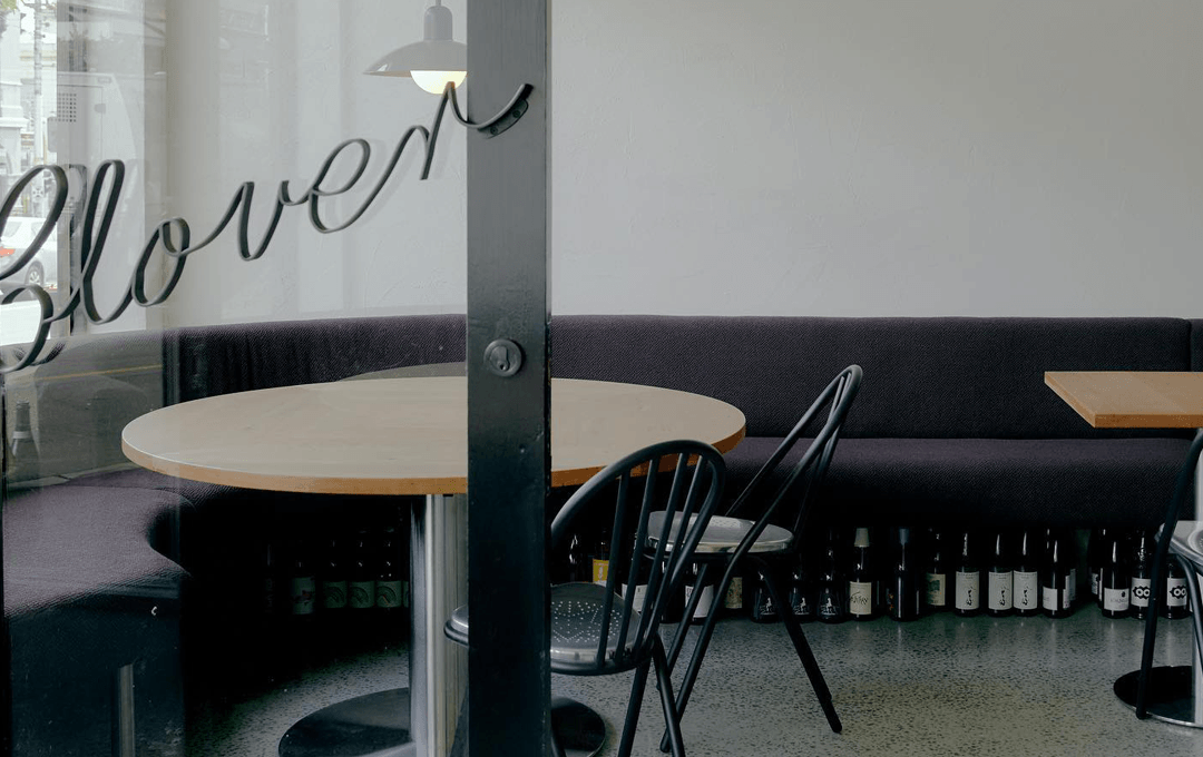A door looking through to a restaurant with tables, chairs and wine bottles. 