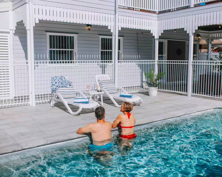 Two guests enjoy the pool at Coastal Corner Airbnb one of the best stays in Townsville 