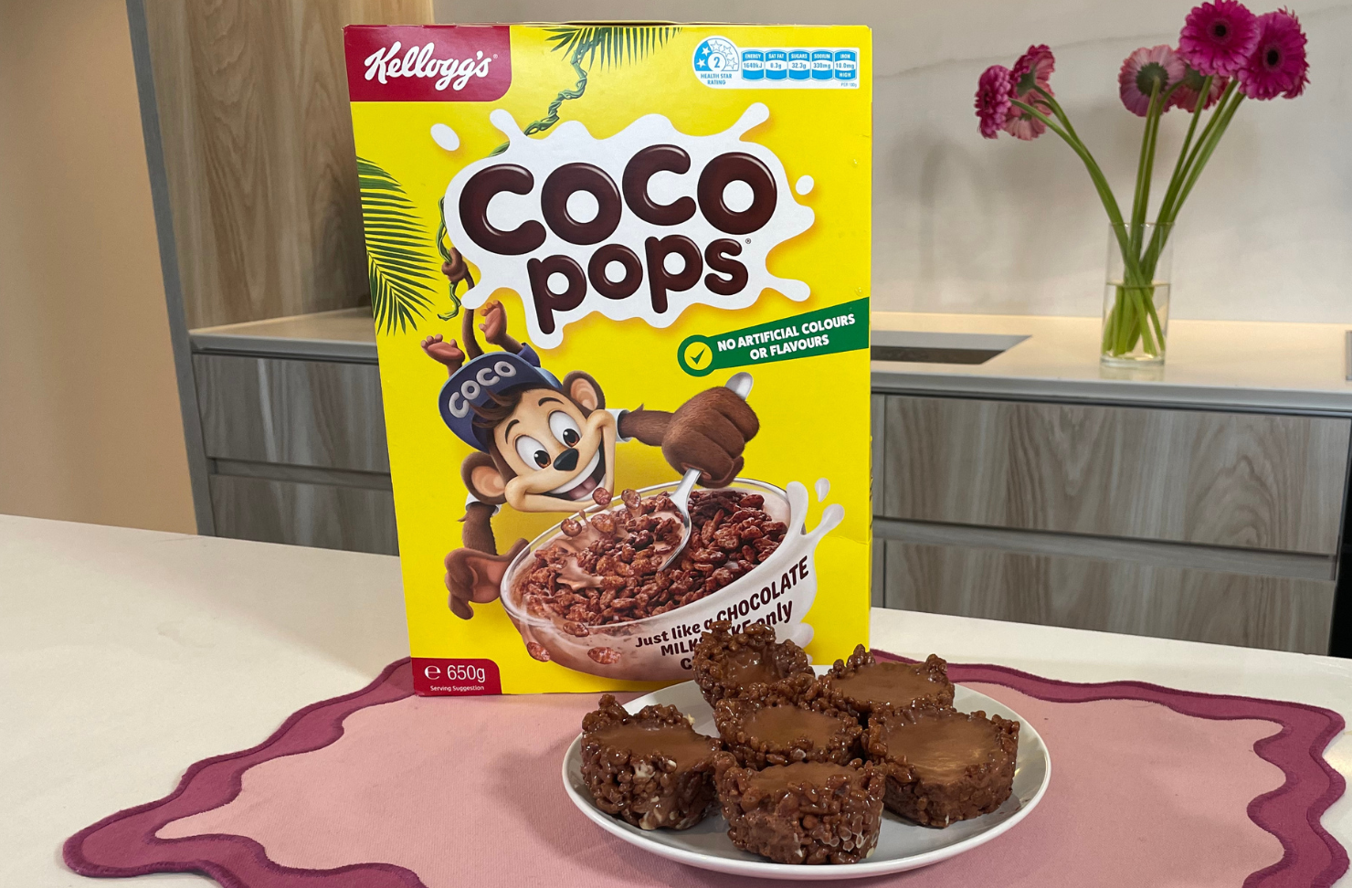 Coco Pops mousse cups on a pink placemat in a kitchen