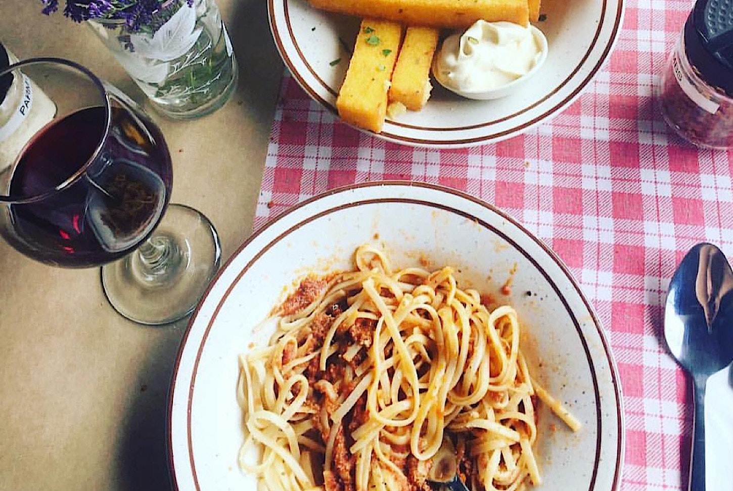 A delectable plate of pasta pomodoro and a glass of red. 