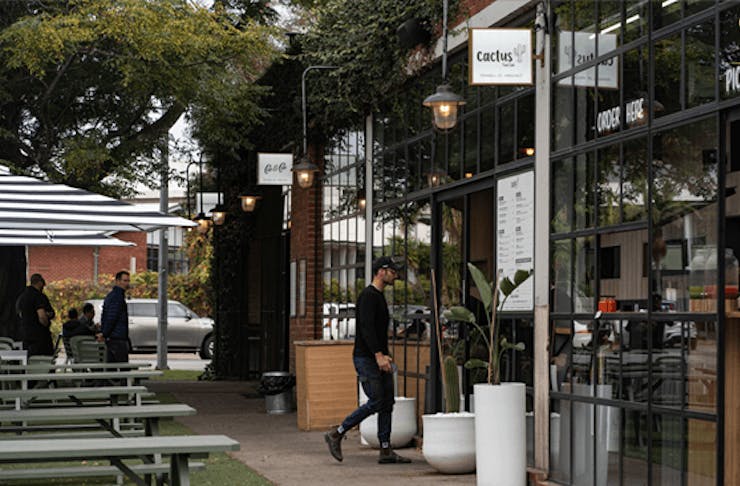 An outdoor dining area with a person walking into a cafe.