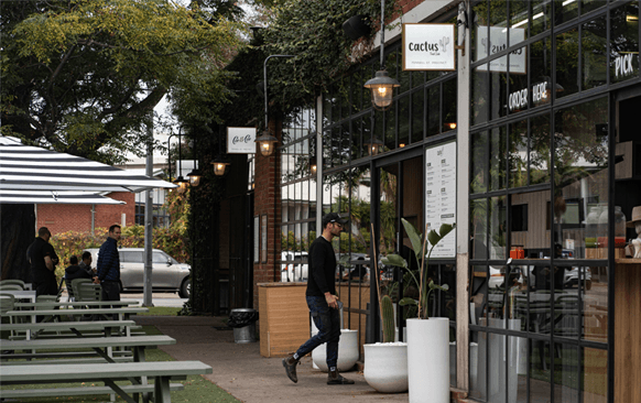 An outdoor dining area with a person walking into a cafe.