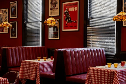 A restaurant with red booths and red and white check tablecloths.