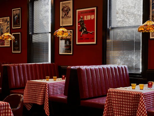 A restaurant with red booths and red and white check tablecloths.