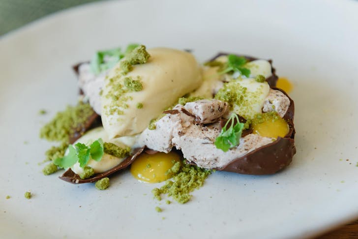 Deconstructed cholocate brownie vanilla Connoisseur ice cream on a plate with custard and matcha soil.