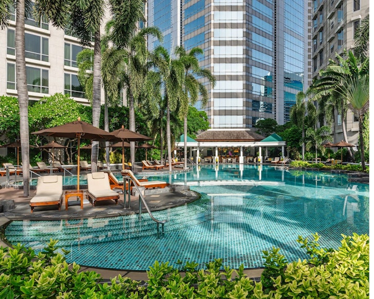 The resort-like pool with palm trees at Conrad Bangkok one of the best Bangkok hotels