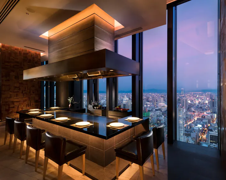 The moody, luxurious dining room with skyline views at Conrad Hotel in Osaka.