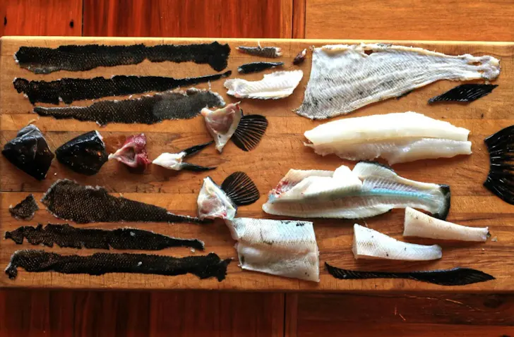 All the pieces of a butterfish arranged on a bread board for cooking