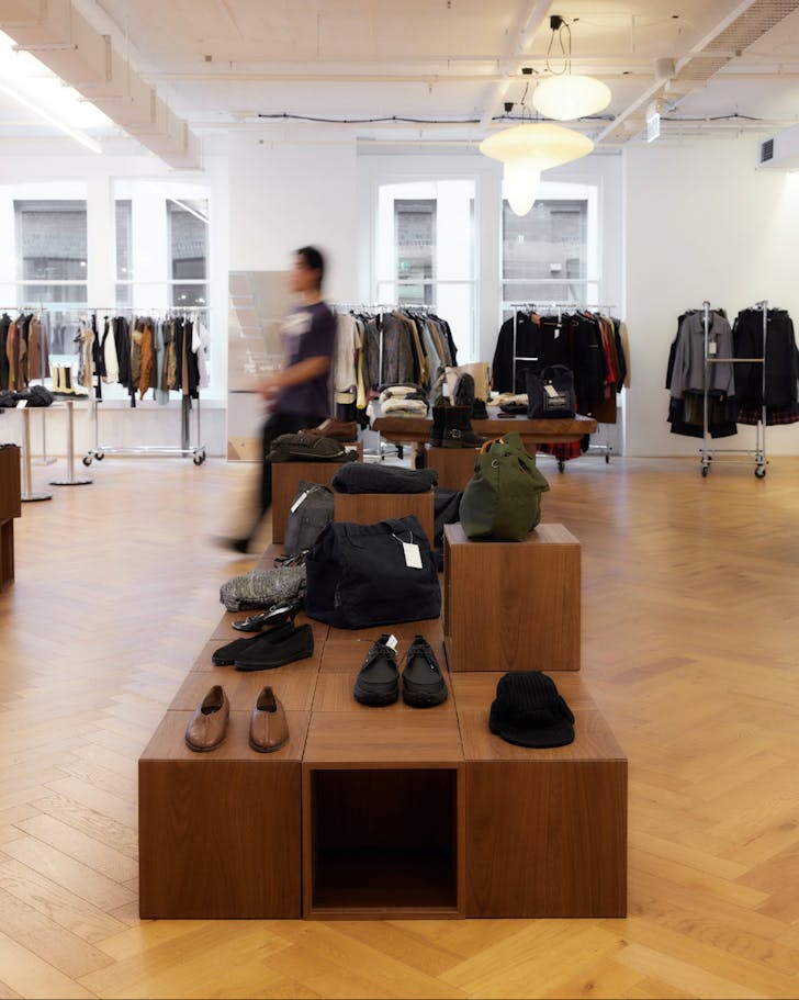 A wide shot of the interior of CCC's Sydney store, where there are racks of clothing minimalistically scattered around the room and accessories like bags displayed on the tables between racks. A man walks through the shop.