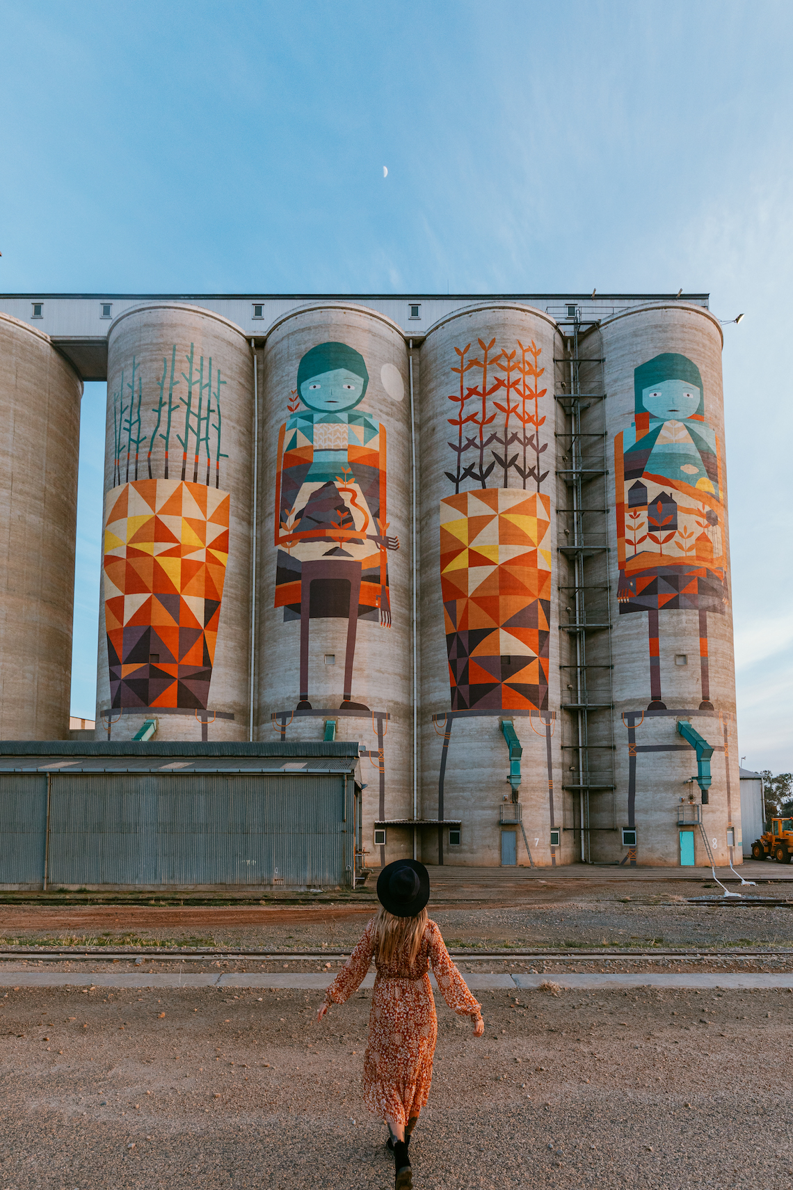 Woman in red dress standing in front of Merredin silos