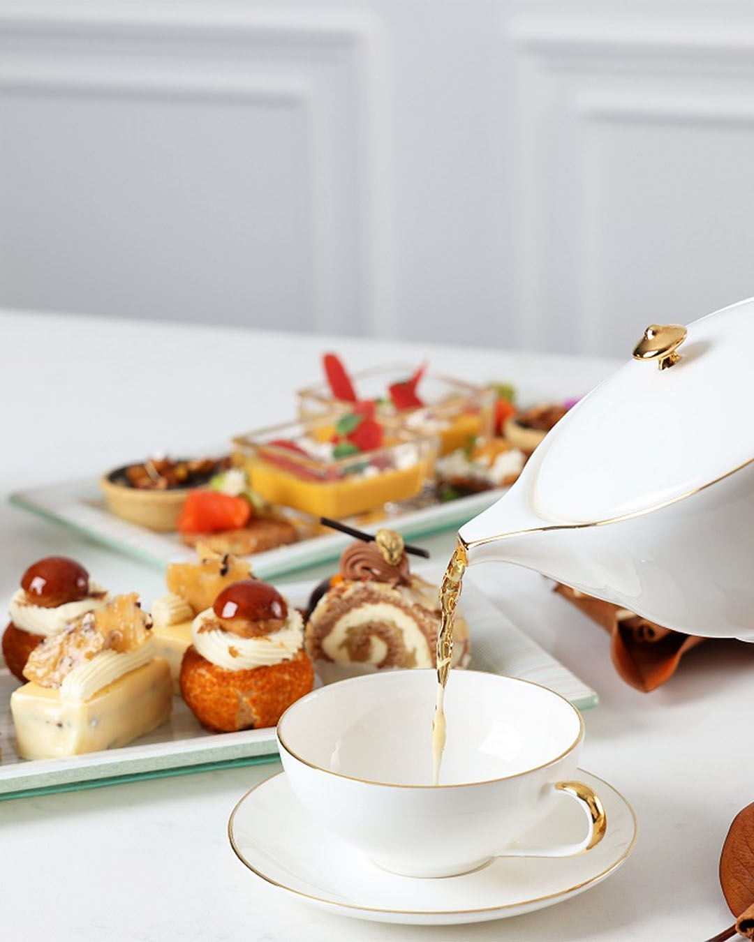 Someone pours a TWG tea into fine china at the Cordis, one of the best high teas in Auckland which is held in the boujee chandelier lounge.