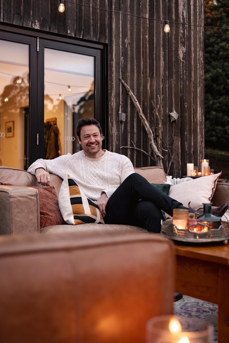 Man sitting on couch with lights and cushions.