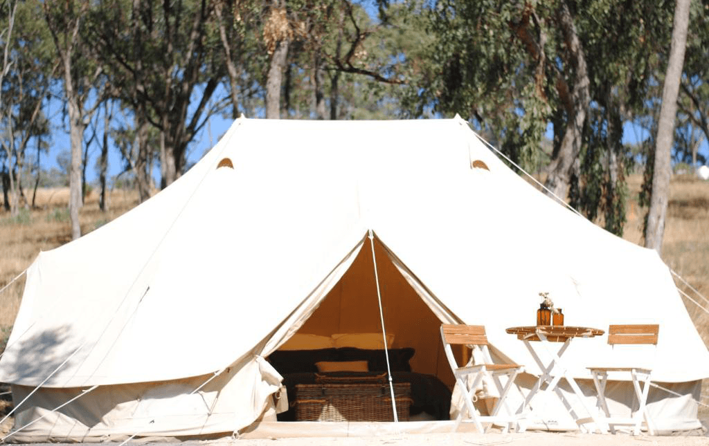 A large belle tent set up in the bush with trees and blue skies, a top glamping victoria spot.