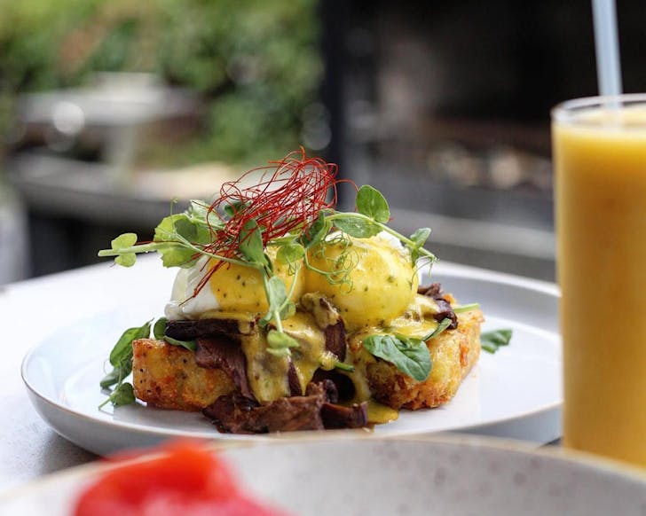 A stacked eggs bene piled up on a kickass potato rosti.