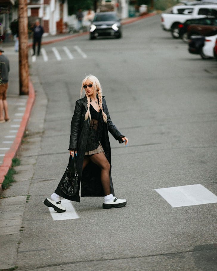 A chic looking woman channeling The Matrix crosses the road wearing Croc loafers. 