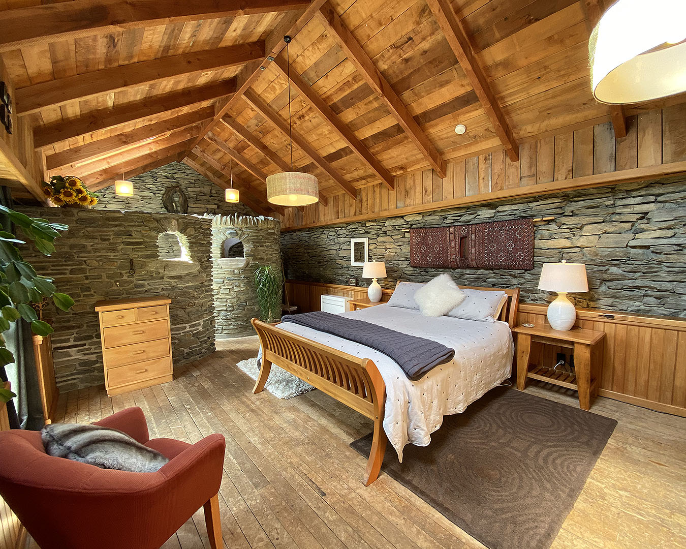 A gorgeous room with a bathroom hidden behind a curved stone wall behind.