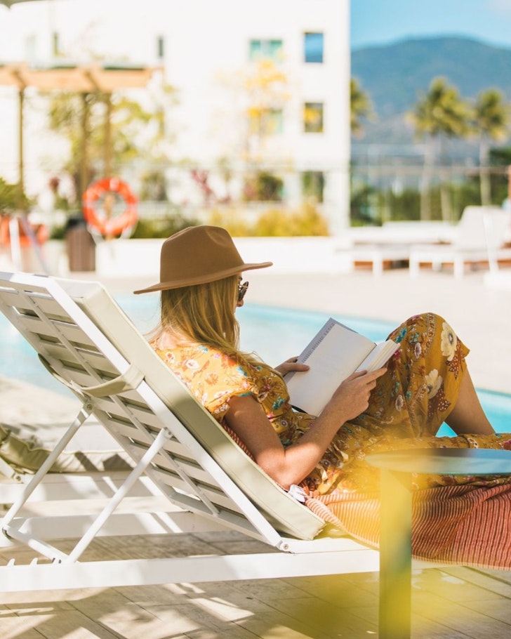 A woman reads a book by the pool at Crystalbrook Bailey hotel Cairns