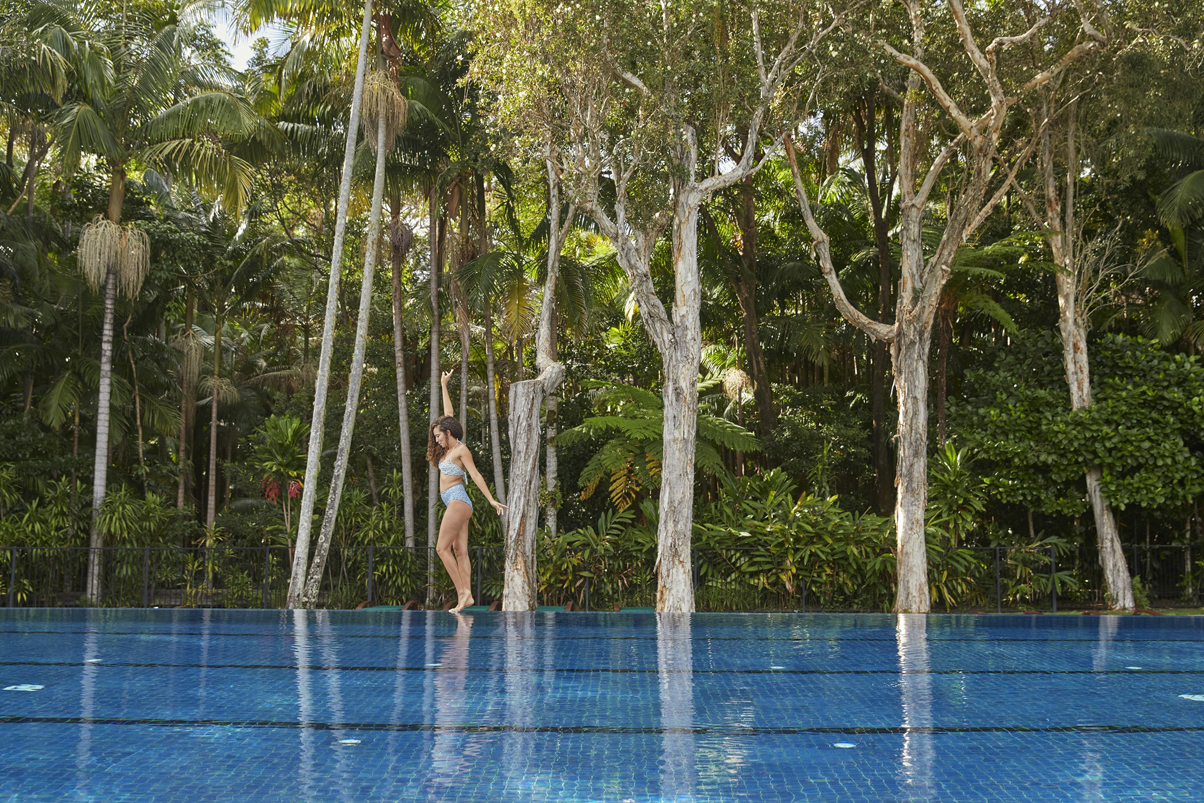 person at edge of pool in front of bush