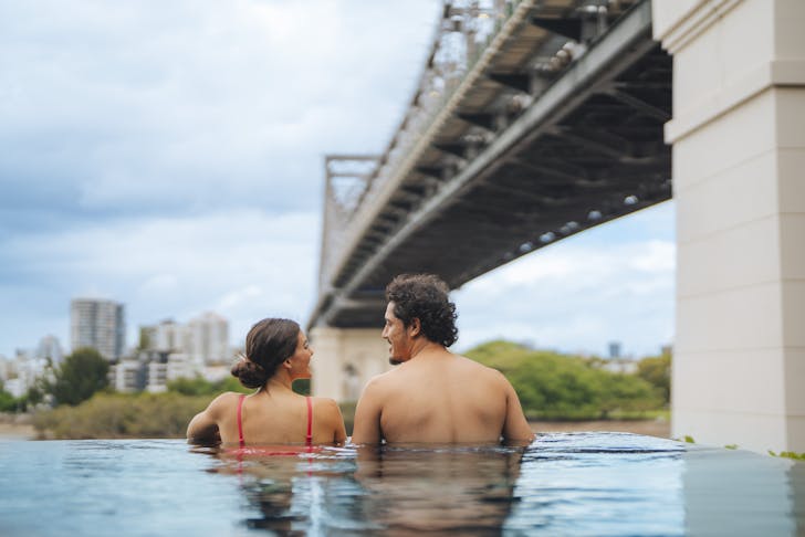 Two people in a pool below bridge