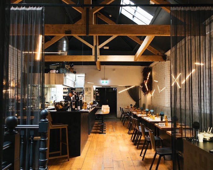 A single file dining set-up opposite an open kitchen.