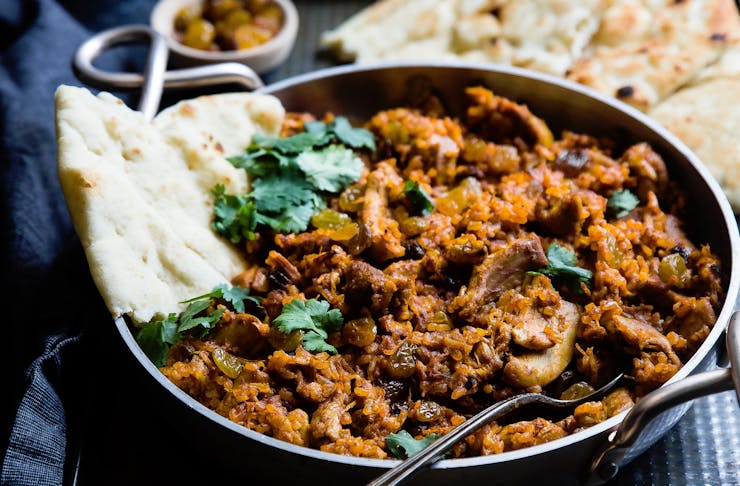 Chunky meat curry sits in a steaming pan. 