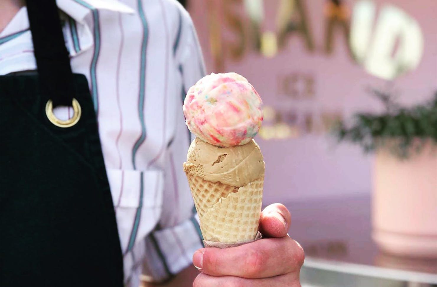 A man holds two scoops of duck island ice cream as he stands outside the store.