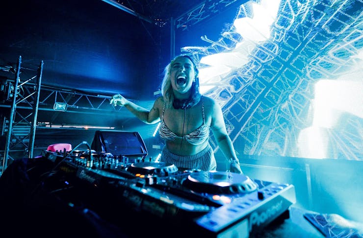 A DJ screams with joy, bathed in blue light, at Rhythm & Vines, one of the best New Year’s Eve parties in New Zealand. 