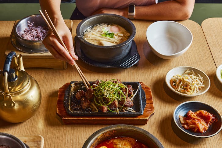Bowls of food with a pair of hands and chopsticks 