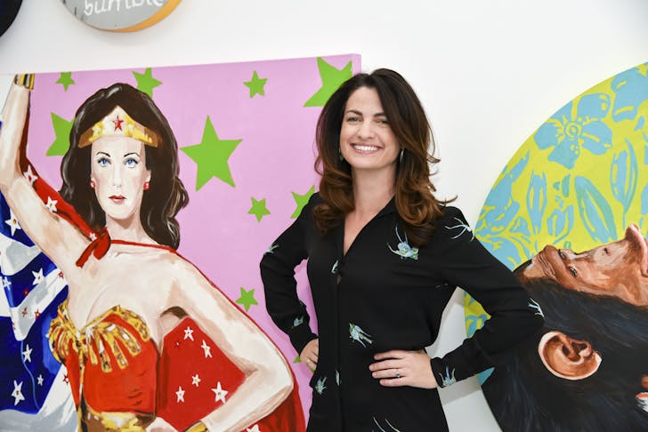 Meggie Palmer stands next to a wonder woman mural.