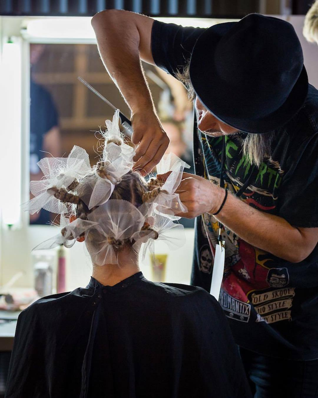 A hairdresser is working on customer to create a beautiful hair design with ribbons.