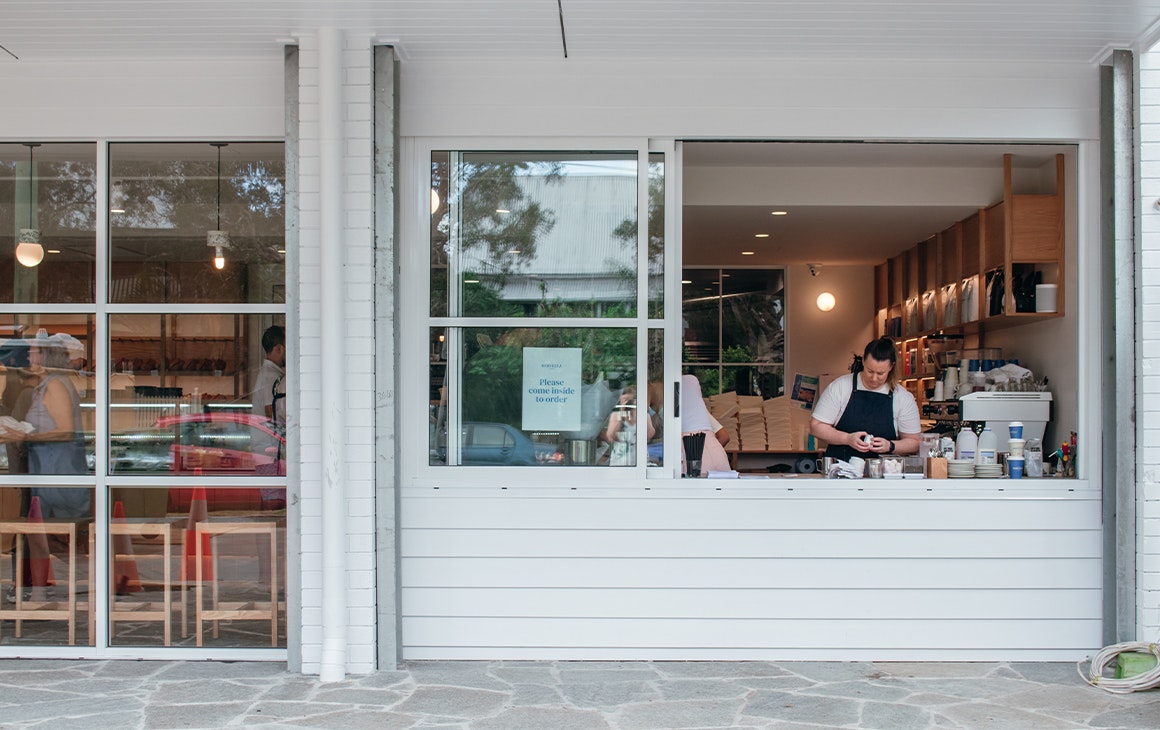 the front window of a bakery, with a coffee machine inside