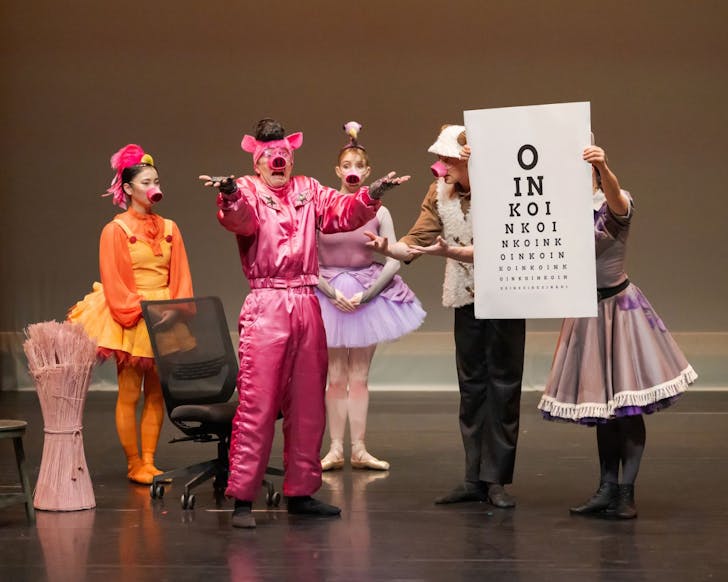 Five ballet performers dressed as animals hold up a sign that says OINK