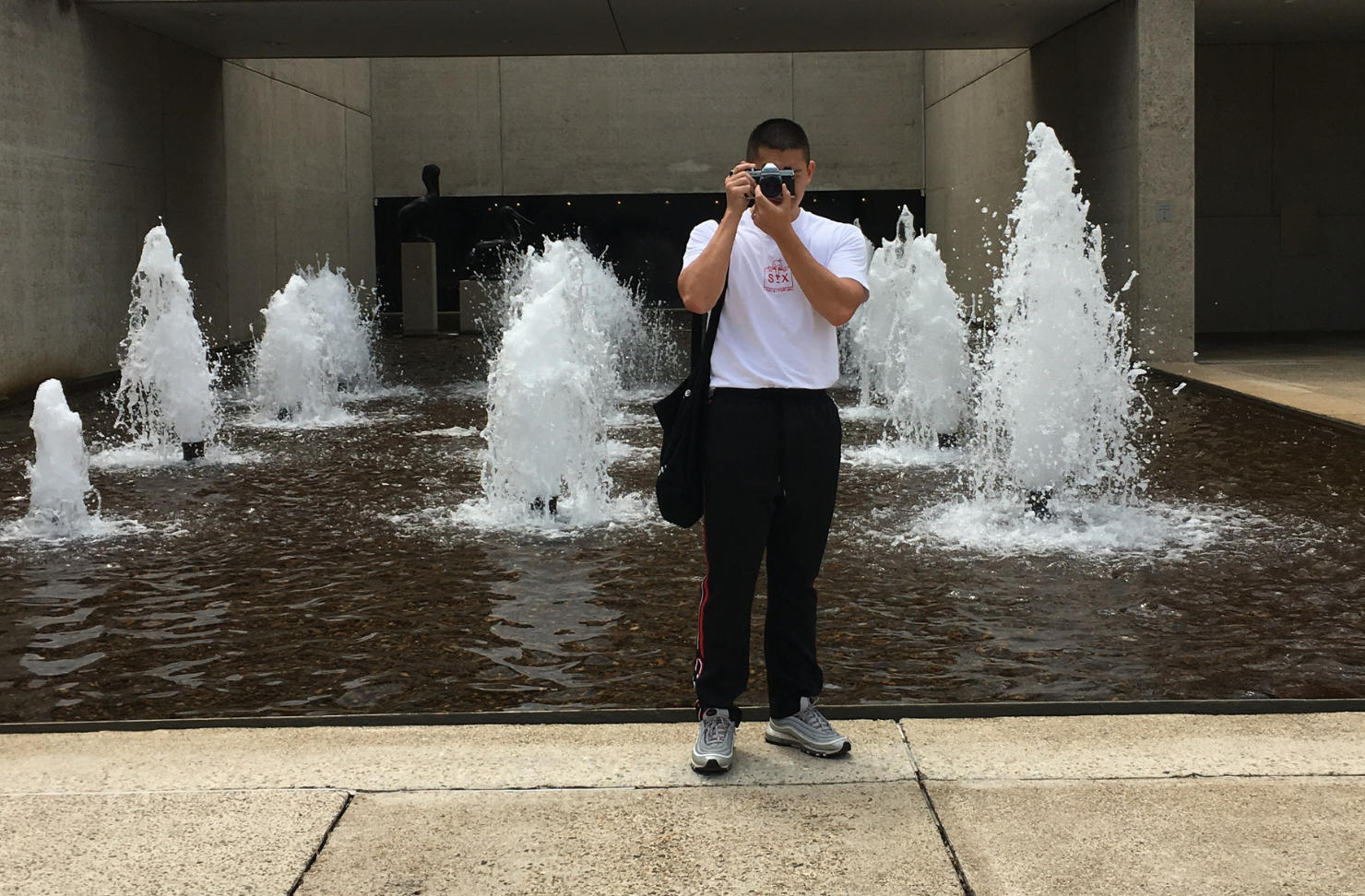 Person holding camera at fountain