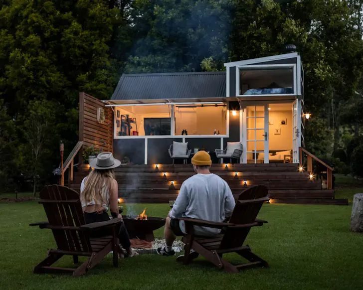 Two guests around the fire pit at Deck and Spa Tiny House Airbnb, some of the best Central Coast accommodation