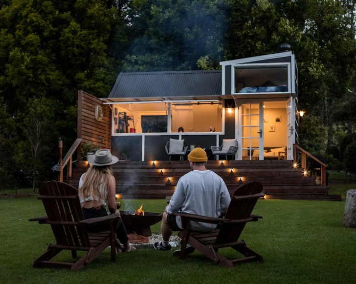 Two guests around the fire pit at Deck and Spa Tiny House Airbnb, some of the best Central Coast accommodation