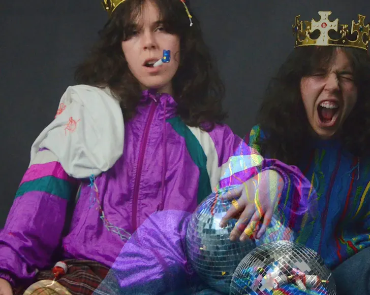 A girl and her doppleganger wear burger king-esque crowns and pull faces. 