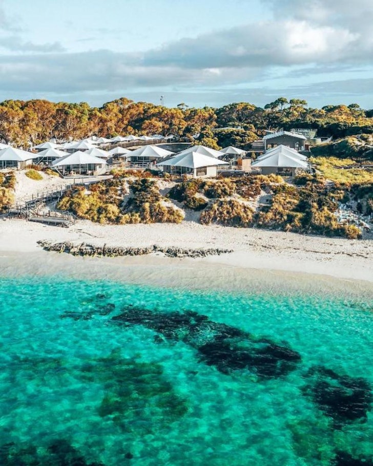 A view of the white glamping tents with the ocean in the foreground at Discovery Rottnest Island one of the best romantic getaways in Australia