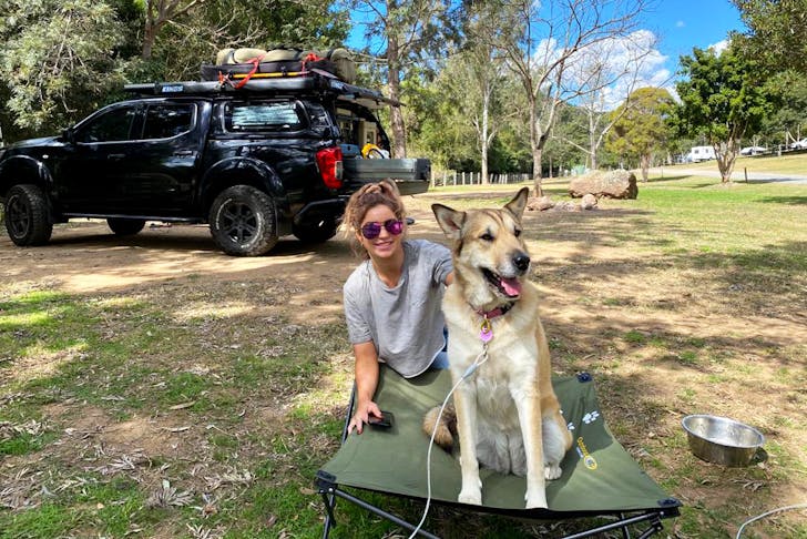 Woman and her dog on a camping bed at a camping site