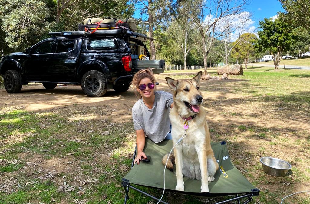 Woman and her dog on a camping bed at a camping site