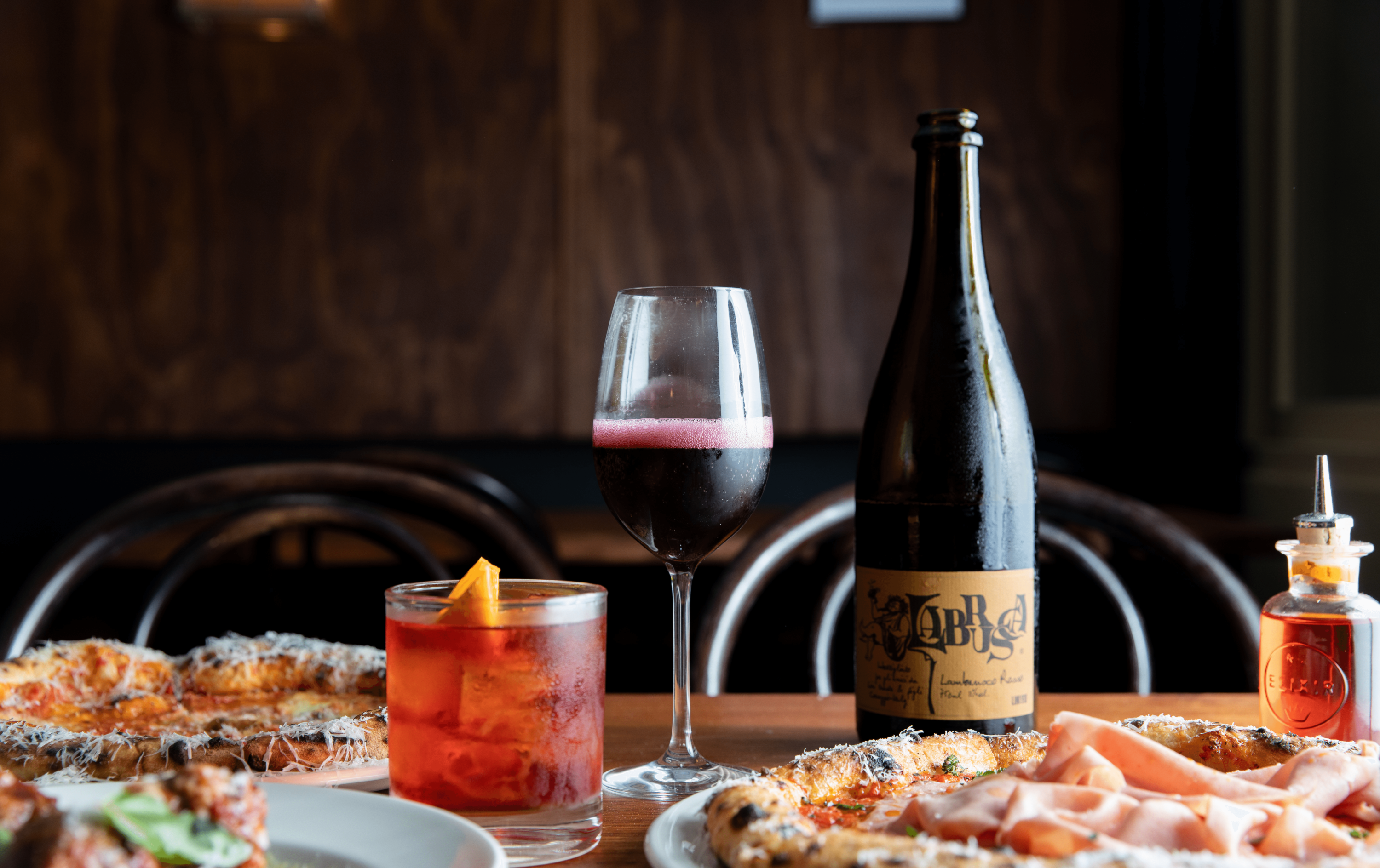 Pizzas a negroni and wine on a table at one of the best bars in Melbourne. 