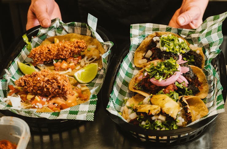 Two trays filled with stacked tacos. 