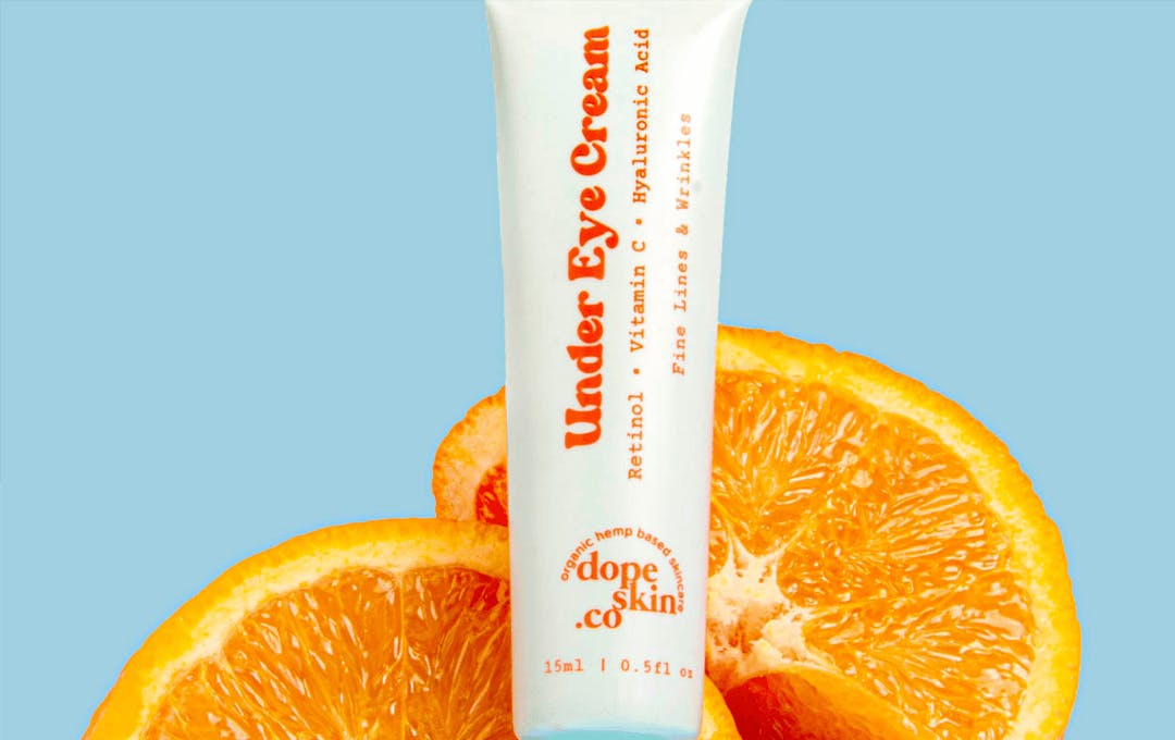A bottle of eye cream with two slices of oranges. 