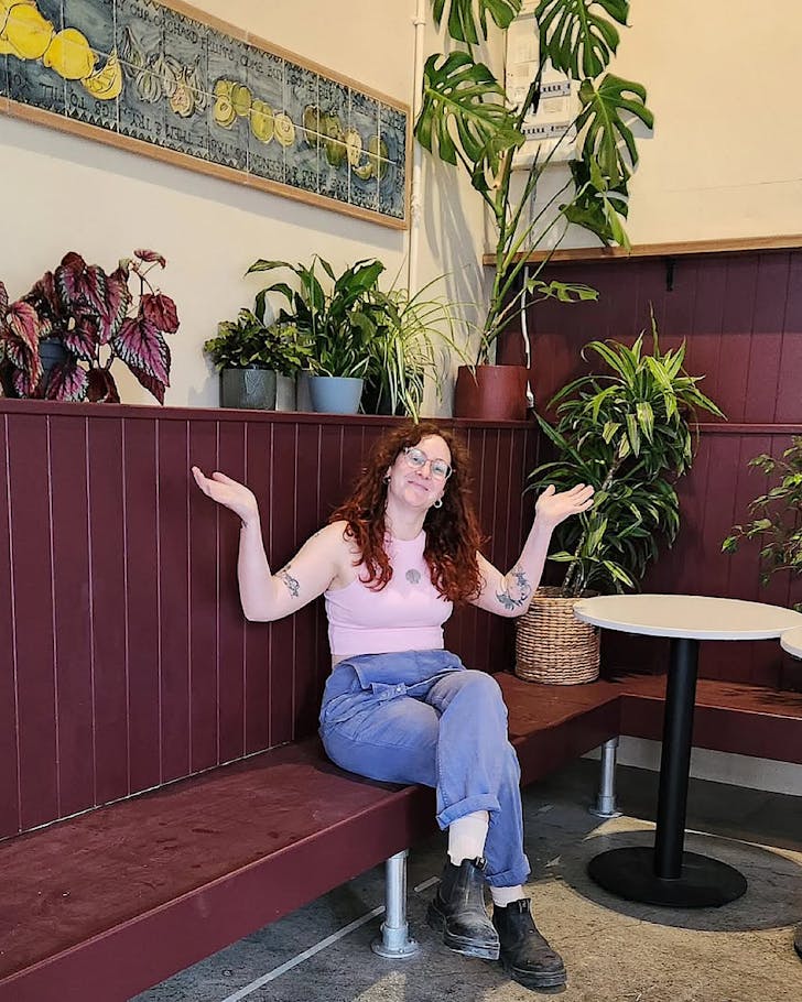 Dori Raphael sits on a bench in Amuse Snack Bar looking stoked.