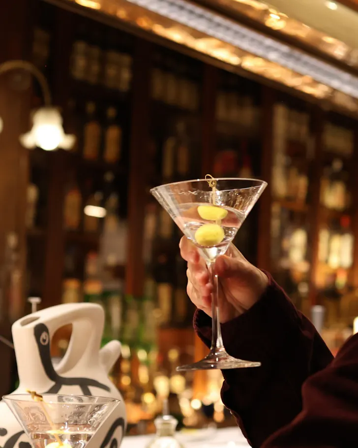 A martini with olives being held up in the atmospheric Dry Martini. 