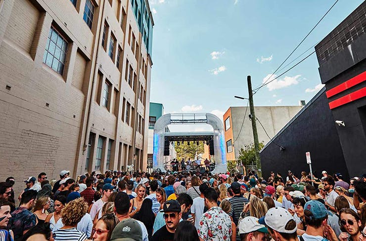 a laneway filled with people dancing in front a stage.